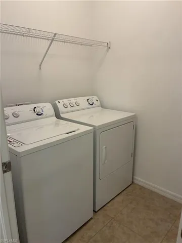 Laundry room with washer and dryer and light tile patterned flooring