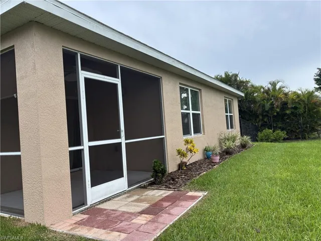 View of side of home with a lawn, stucco siding, and a sunroom