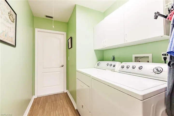 Laundry area featuring cabinets, independent washer and dryer, and light hardwood / wood-style floors