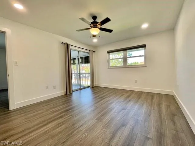 This room features wood-look flooring, white walls, recessed lighting, and a ceiling fan with an integrated light fixture