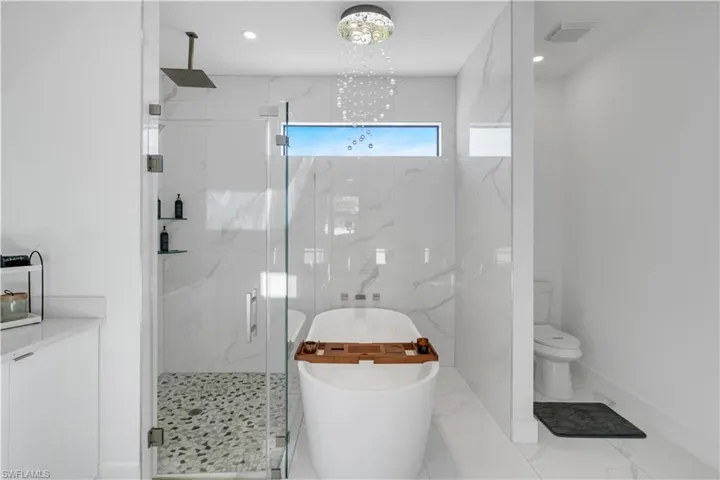 Bathroom with a soaking tub, a marble finish shower, recessed lighting, and marble finish flooring
