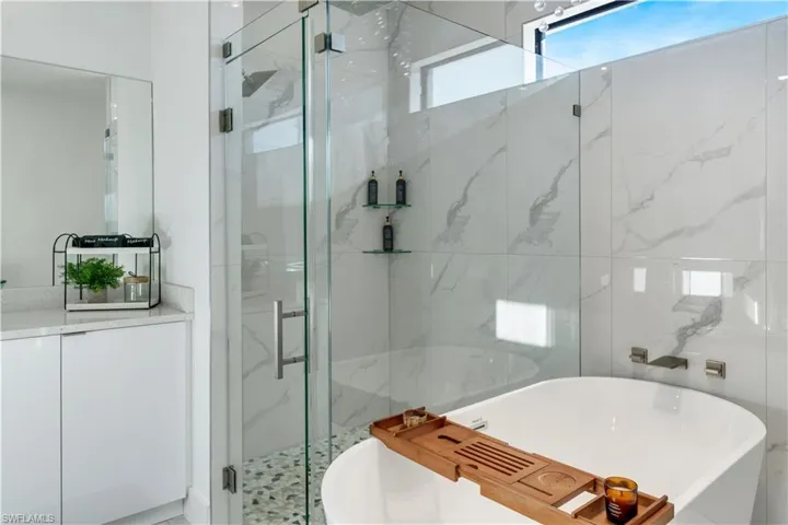 Full bathroom with a soaking tub and a marble finish shower