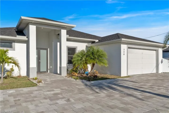 View of front of house with a shingled roof, stucco siding, driveway, and an attached garage