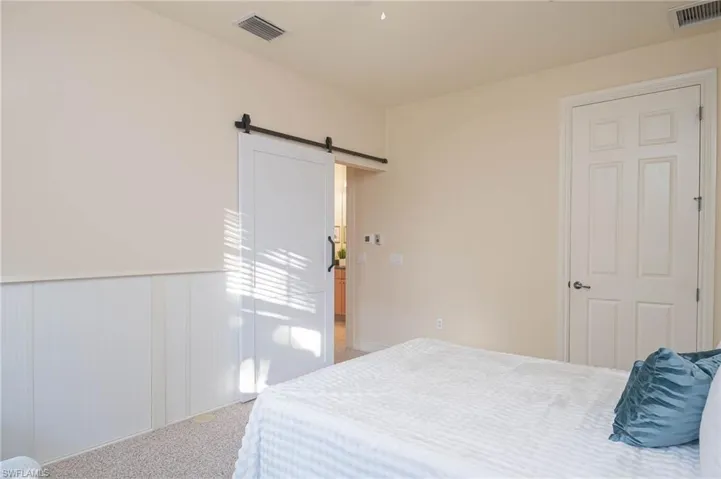 Bedroom with a barn door and light colored carpet
