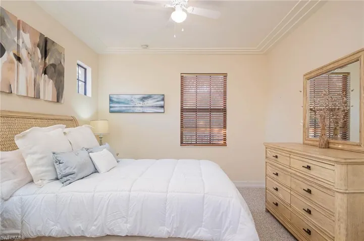 Carpeted bedroom with ceiling fan and crown molding