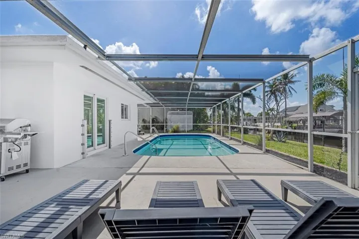 Outdoor pool featuring a patio area, a sunroom, area for grilling, and a lanai