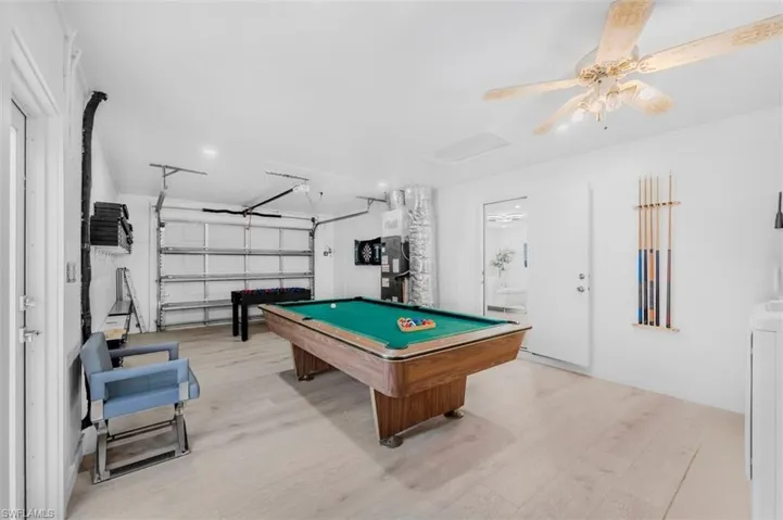 Recreation room with billiards table, light wood-style floors, washer / dryer, ceiling fan, and a garage