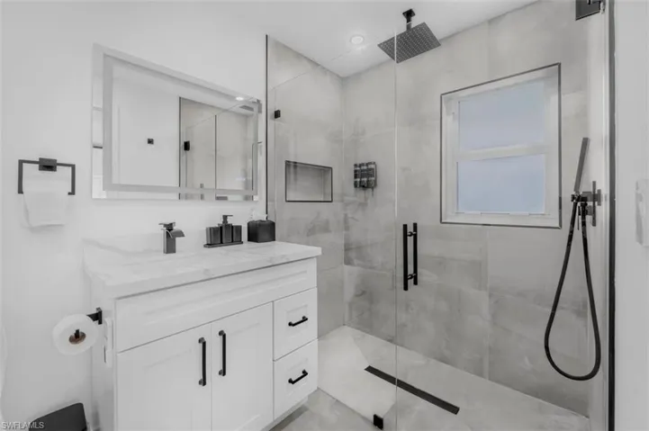 Full bath with a marble finish shower and vanity