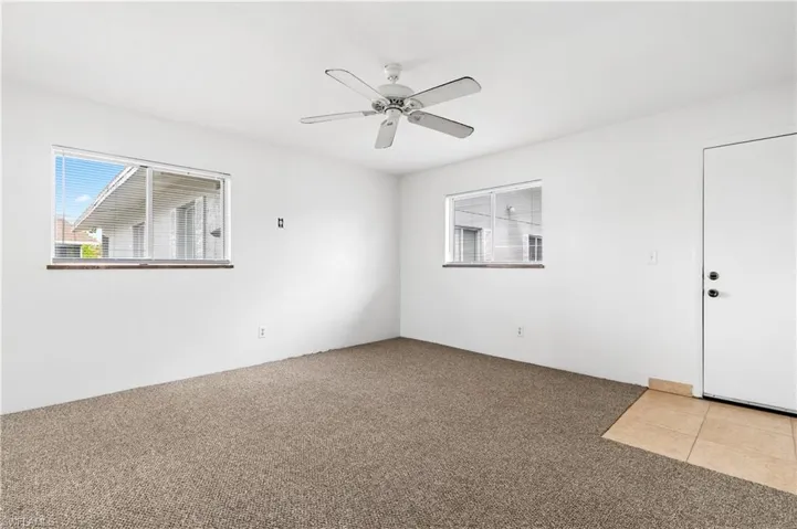 Tiled spare room featuring carpet floors and ceiling fan