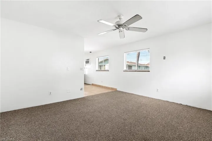 Unfurnished room with a ceiling fan and light carpet