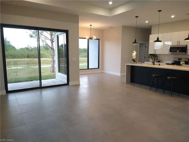 Kitchen with tile patterned flooring, a chandelier, pendant lighting, white cabinets, and appliances with stainless steel finishes
