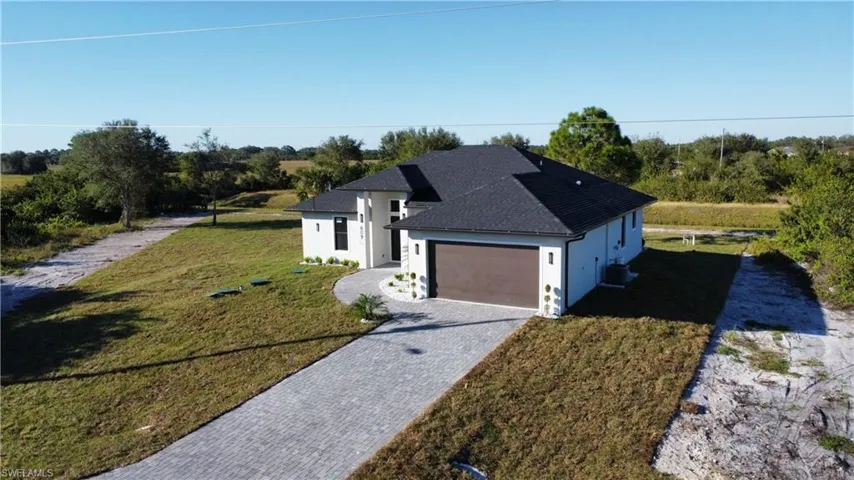 View of front of property with a front yard, central AC, and a garage