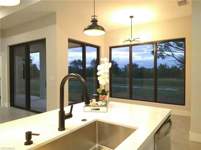 Kitchen with sink, pendant lighting, an inviting chandelier, dishwasher, and tile patterned flooring