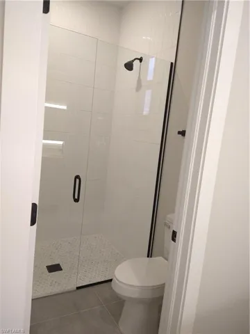 Bathroom with toilet, tile patterned floors, and walk in shower