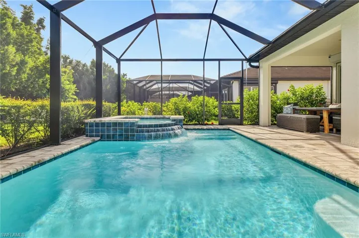 View of pool with a pool with connected hot tub, a patio area, and a lanai