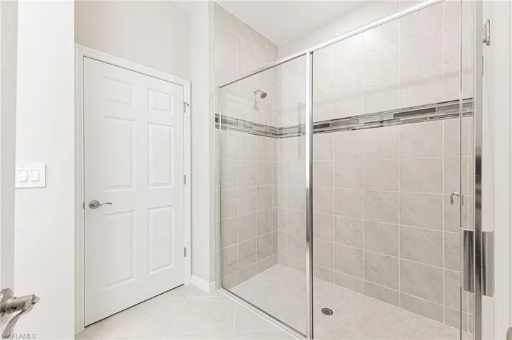 Bathroom featuring a shower stall and tile patterned floors
