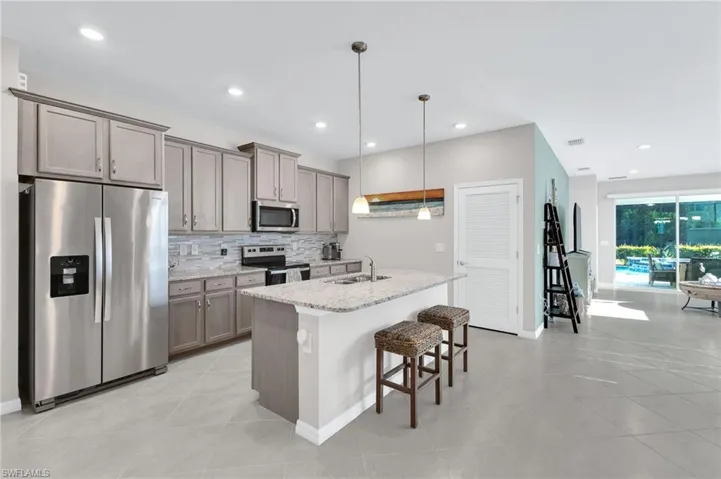 Kitchen with stainless steel appliances, tasteful backsplash, a kitchen breakfast bar, an island with sink, and light tile patterned flooring