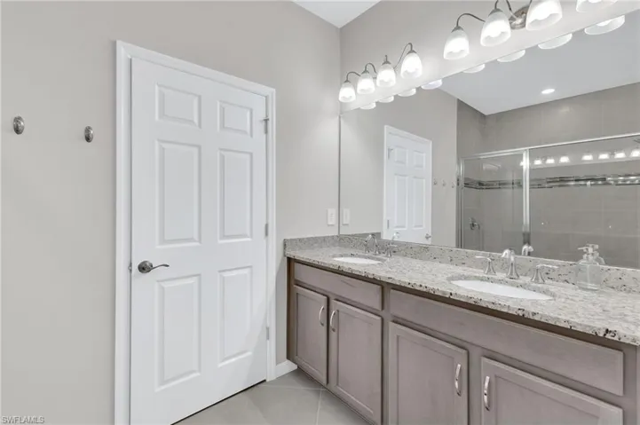 Bathroom featuring a stall shower, double vanity, and tile patterned flooring