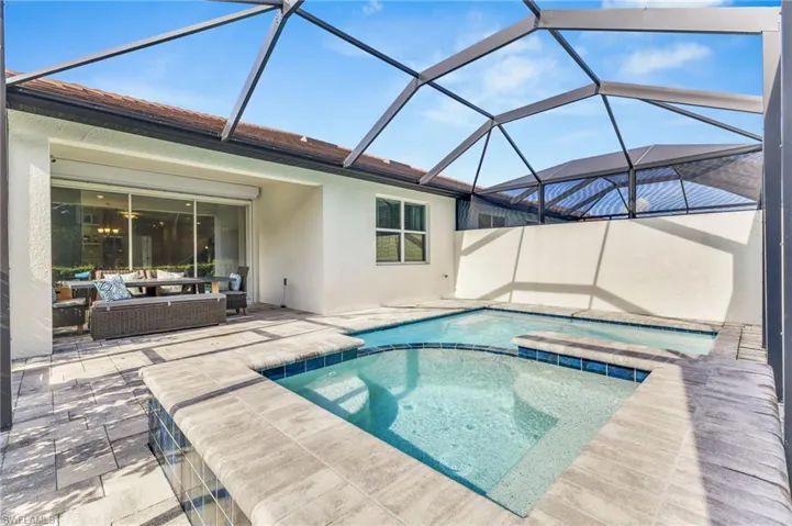 View of pool with outdoor lounge area, a pool with connected hot tub, and a patio area
