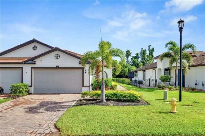View of front facade featuring stucco siding, decorative driveway, a front lawn, and an attached garage