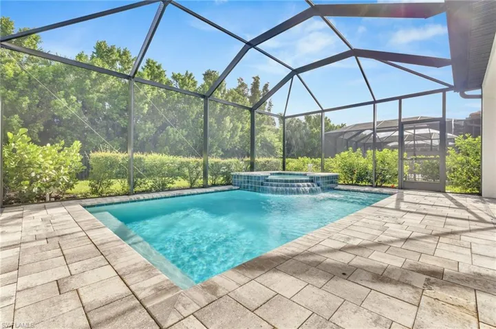 View of swimming pool featuring a patio, a pool with connected hot tub, and a lanai