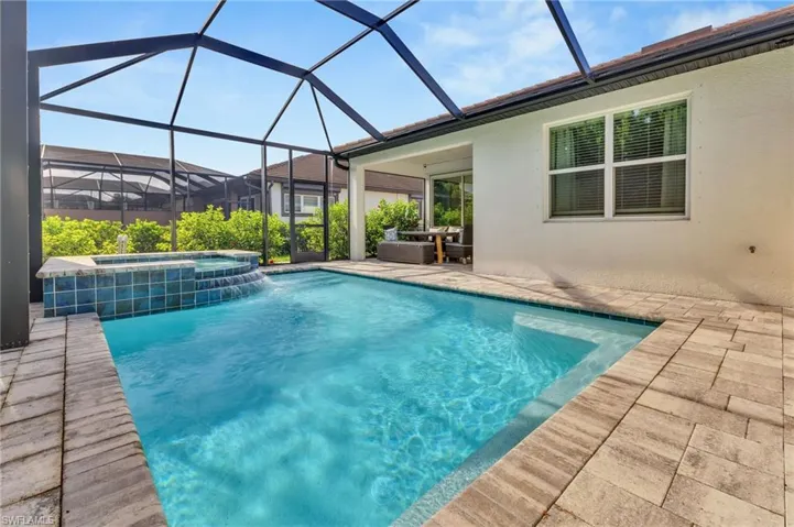 View of pool featuring a pool with connected hot tub, a patio area, and a lanai
