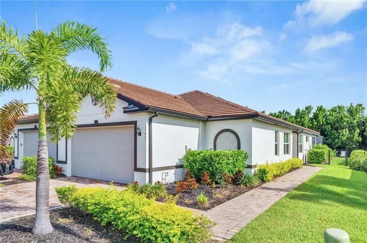 View of side of home with an attached garage, a tiled roof, stucco siding, and driveway