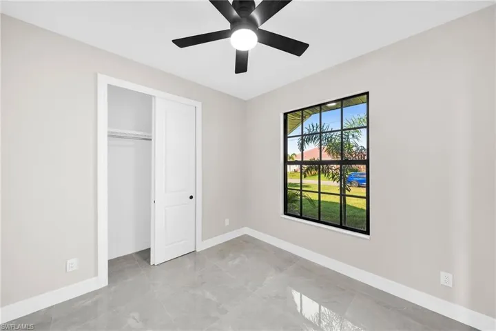 Unfurnished bedroom featuring a closet, ceiling fan, light tile floors, and multiple windows