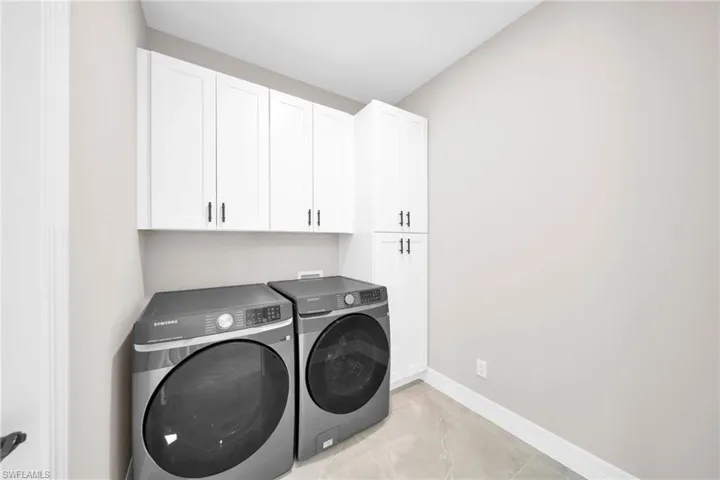 Washroom featuring cabinets, light tile flooring, washer and clothes dryer, and washer hookup