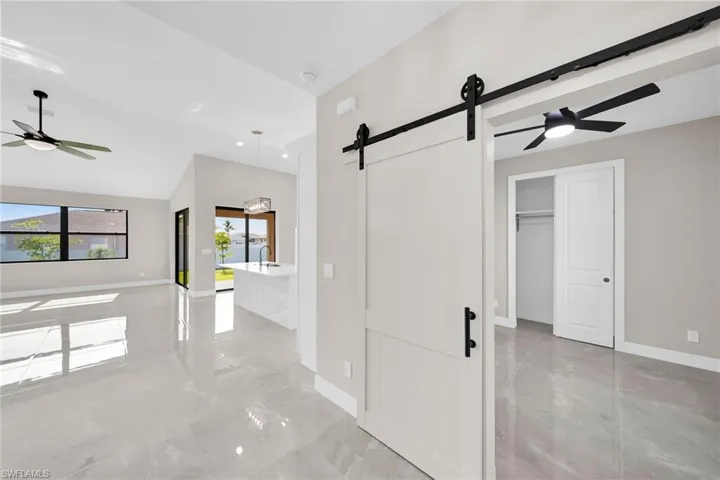 Hall with a barn door, lofted ceiling, and light tile flooring