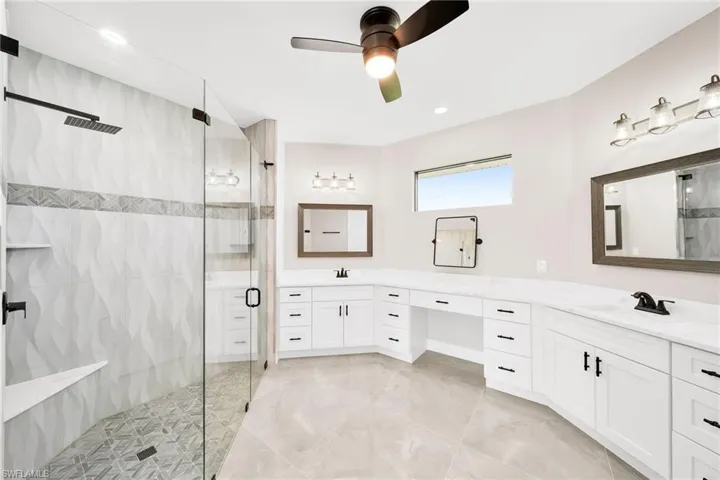 Bathroom with a shower with shower door, ceiling fan, tile floors, and large vanity