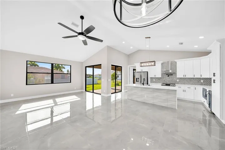 Kitchen featuring a kitchen island, hanging light fixtures, tasteful backsplash, ceiling fan, and light tile floors