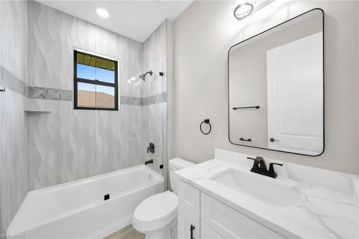 Full bathroom featuring vanity, toilet, and tiled shower / bath combo