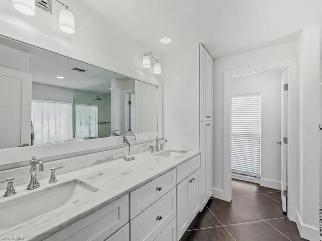 Full bath with a stall shower, double vanity, dark tile patterned floors, and recessed lighting