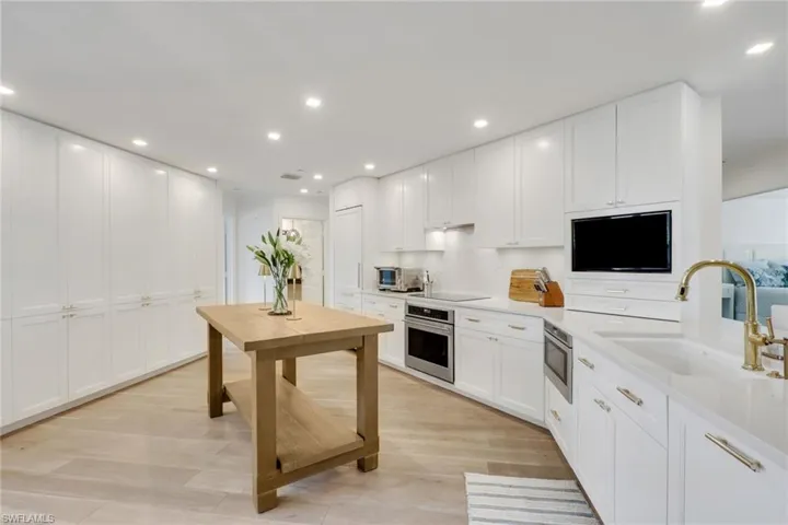 Kitchen featuring white cabinets, recessed lighting, stainless steel appliances, light wood-type flooring, and light stone countertops