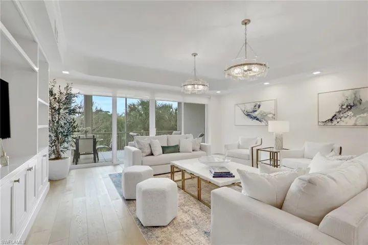Living area featuring real wood flooring, suspended lighting, and a tray ceiling