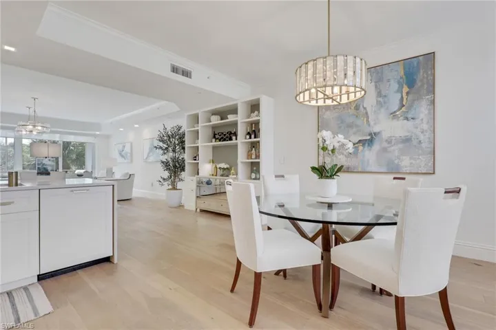 Dining area with a chandelier, light wood-type flooring, a tray ceiling, and ornamental molding