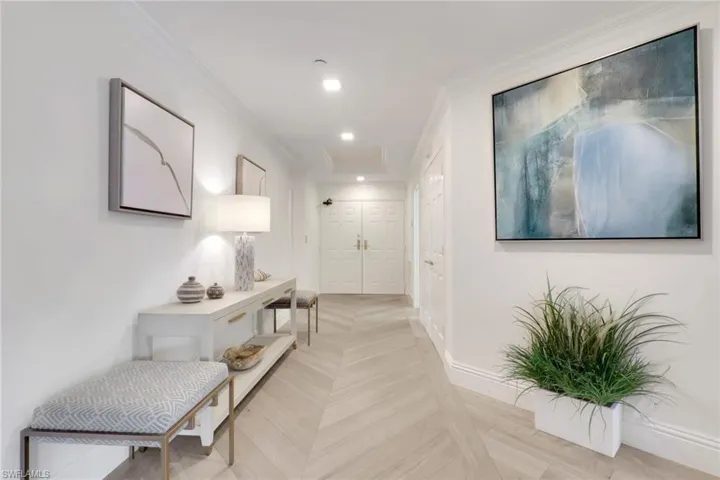 Corridor with ornamental molding, recessed lighting, and  chevron wood entry flooring.