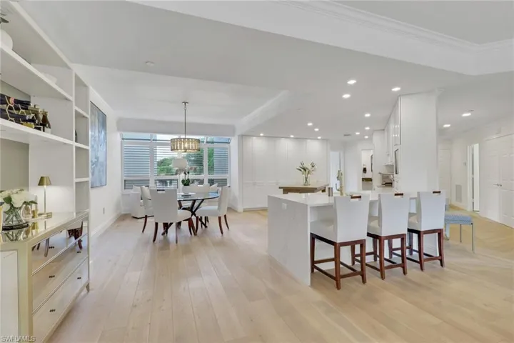 Kitchen with a kitchen breakfast bar, white cabinetry,  real wood flooring, a peninsula, and quartz countertops