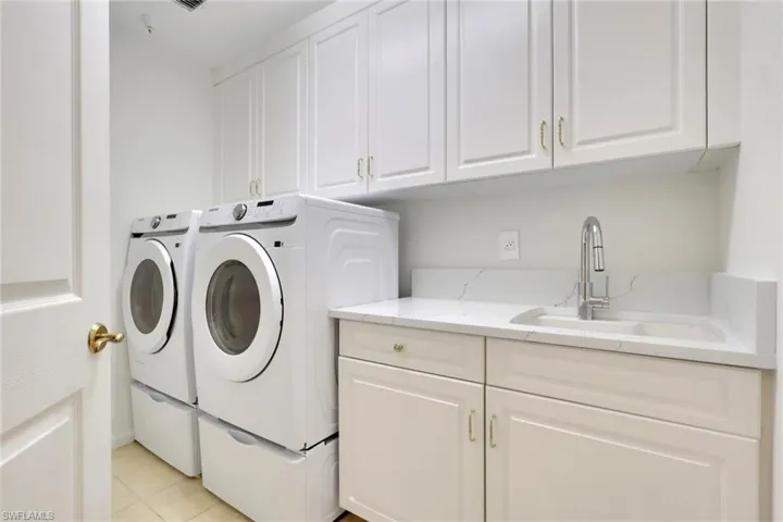Laundry room featuring washer and clothes dryer, cabinet space, and light tile patterned floors
