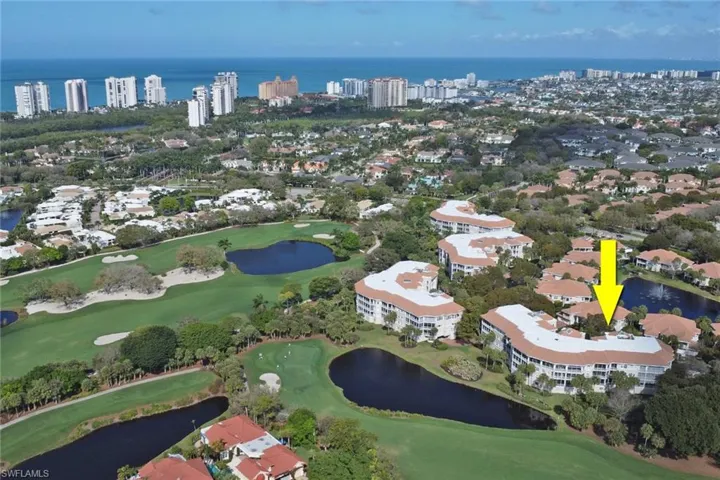 Aerial view of property and surrounding area with a nearby body of water and a golf club