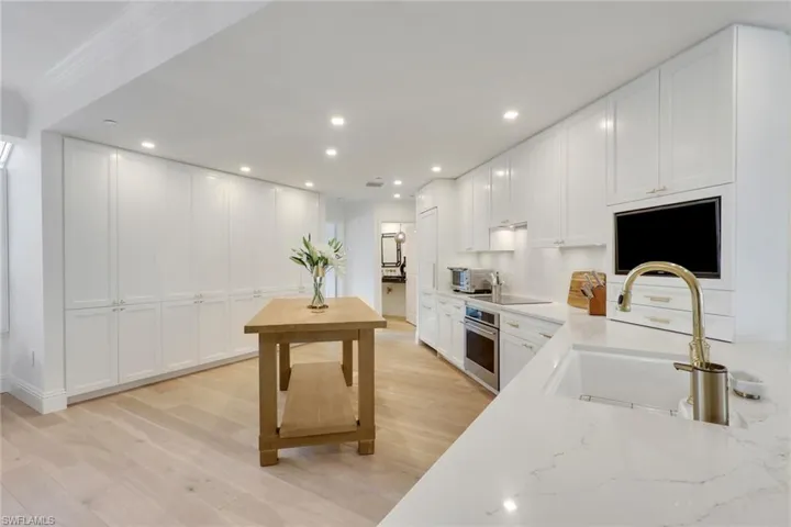 Kitchen featuring white cabinetry, real wood flooring, recessed lighting, quartz countertops, and stainless steel appliances