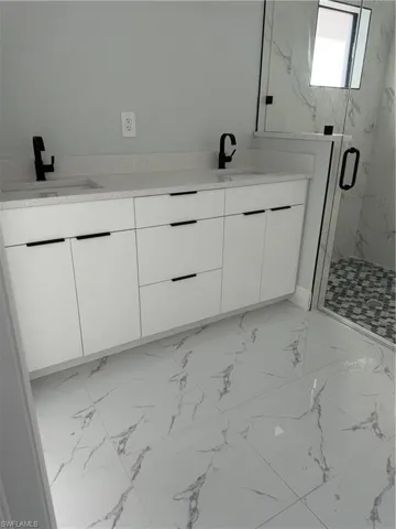 Full bath featuring vanity, shower / bath combination, and light marble finish flooring