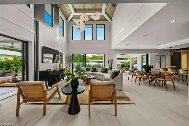 Living room featuring high vaulted ceiling, beamed ceiling, light wood finished floors, and a fireplace