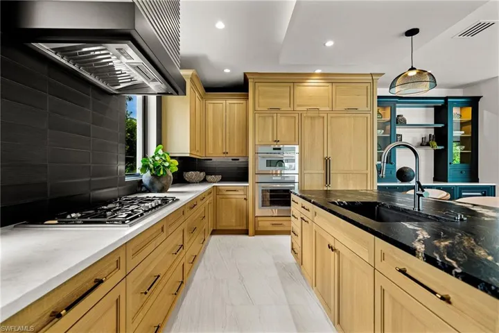 Kitchen featuring appliances with stainless steel finishes, wall chimney exhaust hood, recessed lighting, decorative backsplash, and dark stone countertops