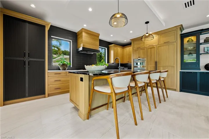 Kitchen with tasteful backsplash, a breakfast bar, an island with sink, pendant lighting, and stainless steel double oven