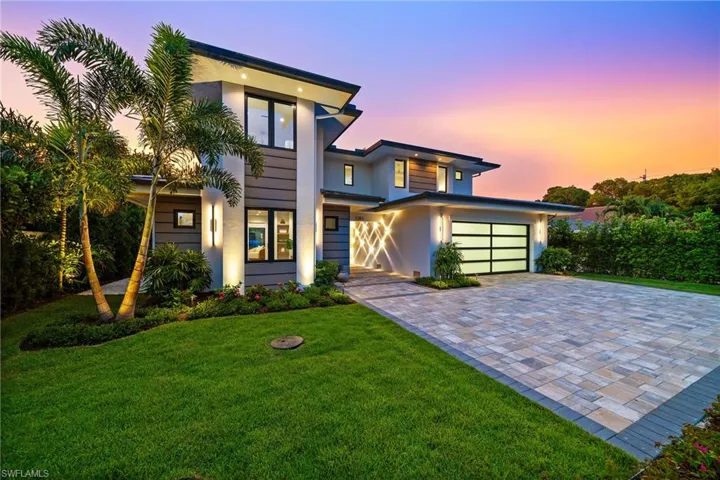 Contemporary home with decorative driveway, stucco siding, and a lawn