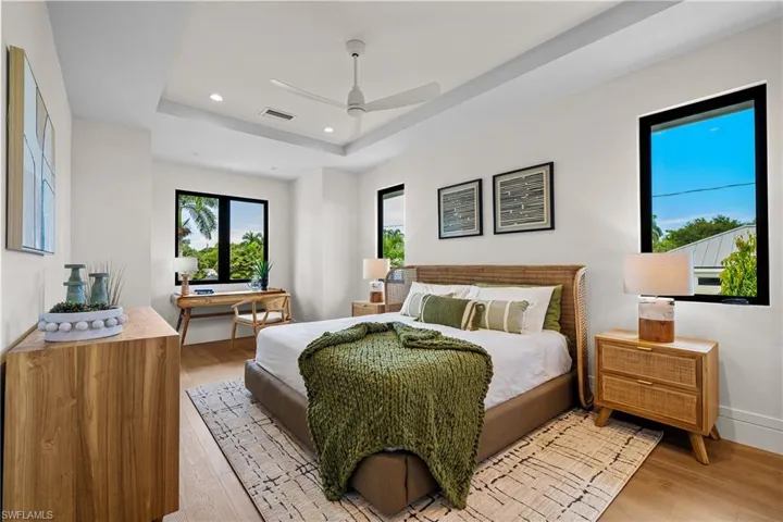 Bedroom featuring light wood finished floors, recessed lighting, a tray ceiling, and a ceiling fan