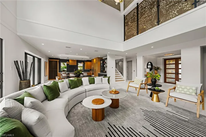 Living room with a high ceiling, stairs, and recessed lighting