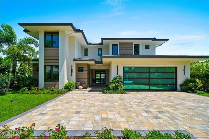 View of front of home featuring stucco siding, decorative driveway, a garage, and french doors
